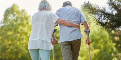 Senioren-Paar mit Krücken läuft gemeinsam